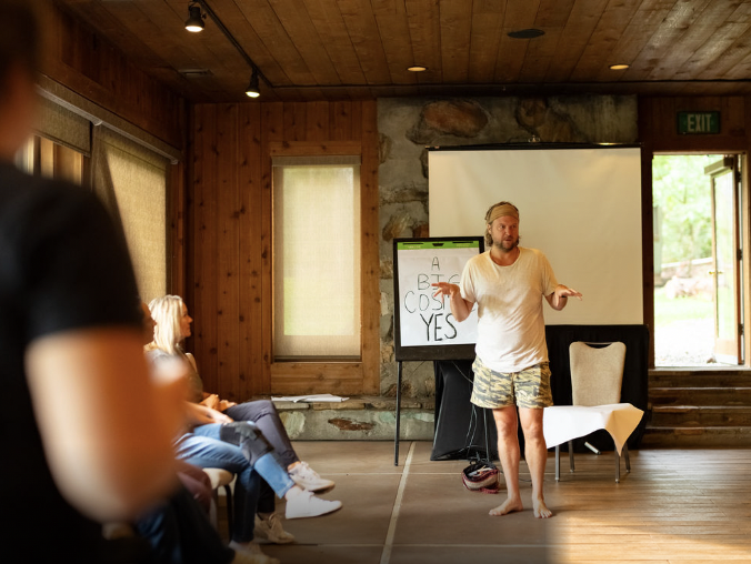 Ryan standing barefoot beside a flipchart reading A Big Cosmic Yes