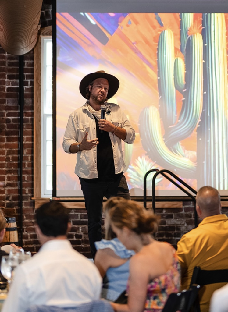 Ryan Wegenast facilitating a session, microphone in hand, in front of a projected illustration